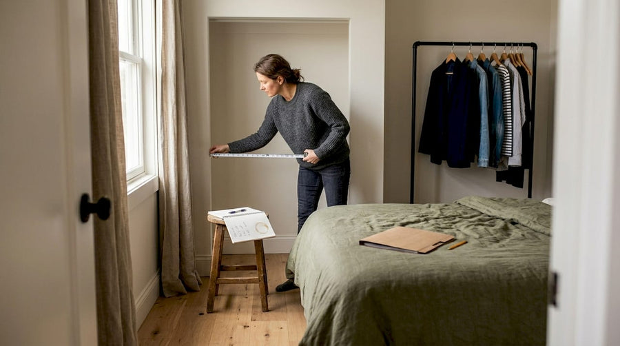 Een vrouw neemt de maten op van haar slaapkamer om te kijken of de kledingkast past.